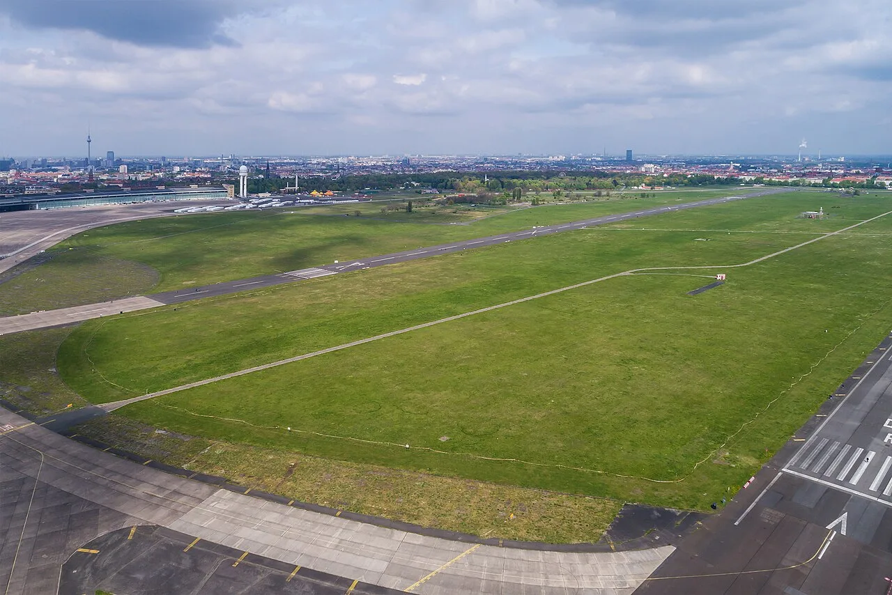 Het Tempelhofer Feld in Berlijn, de enorme open grasviaktes van de voormalige luchthaven Tempelhof met het monumentale stationsgebouw op de achtergrond